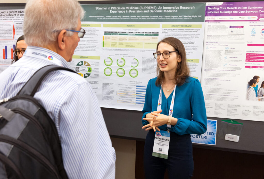 Someone standing in front of their research poster and presenting it to another attendee