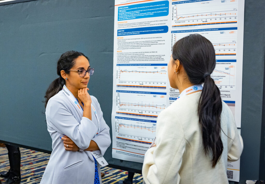 One medical researcher sharing their research with another scientist in the poster gallery of a past NORD event